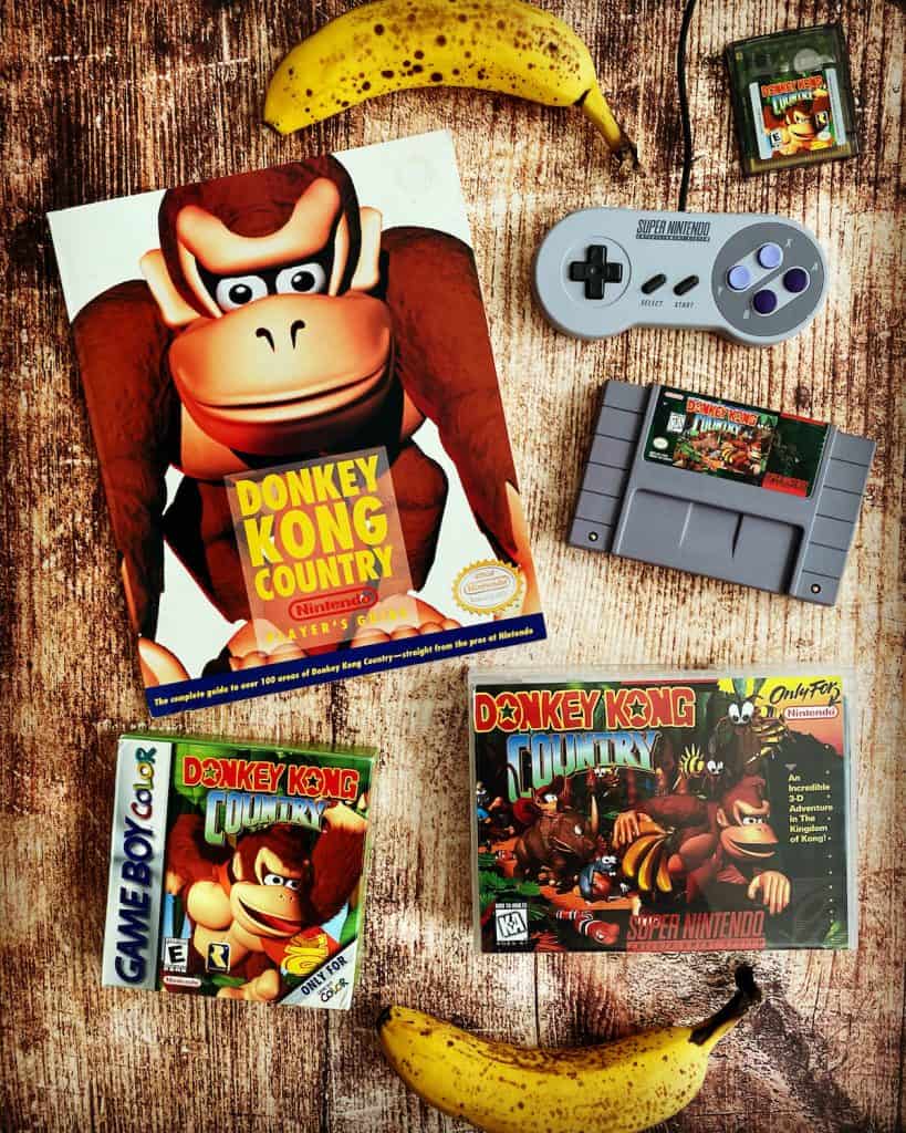 Donkey Kong Country SNES cart, player's guide, Game Boy Color box, Super Nintendo controller, and bananas